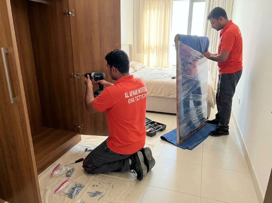 Al Afnan furniture movers carrying a wardrobe wrapped in a furniture pad and stretch film